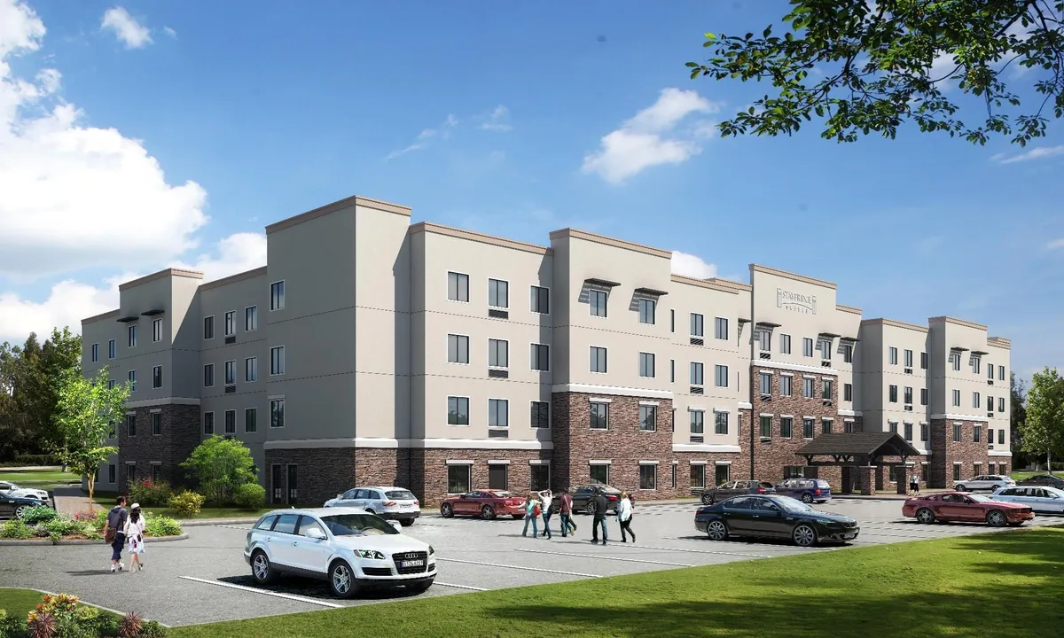 A welcoming exterior shot of the Staybridge Suites St Louis - Westport, featuring the main entrance with its inviting awning and well-maintained landscaping. The image suggests a lively, family-friendly atmosphere with ample space for guests to arrive and gather, and hints at the hotel's proximity to local attractions.
